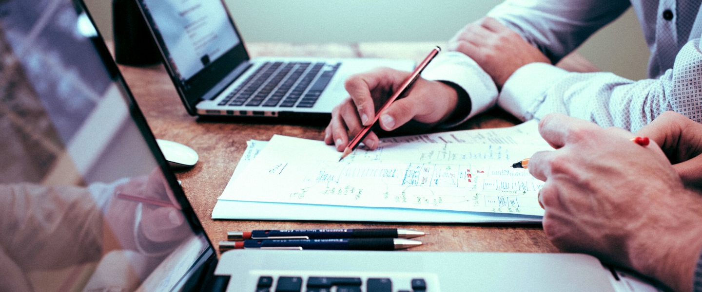 Two people with laptops and work documents on desk